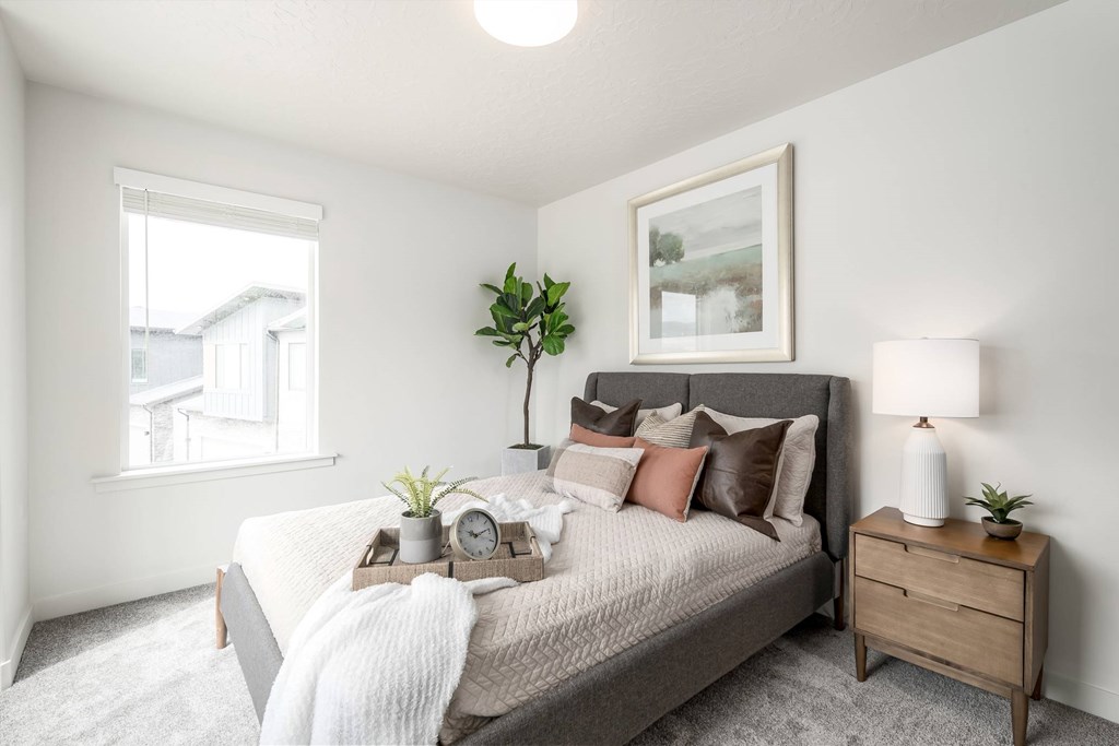 A bedroom with a bed, nightstand, and a window.