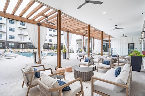 A patio with wooden furniture and a pool in the background.