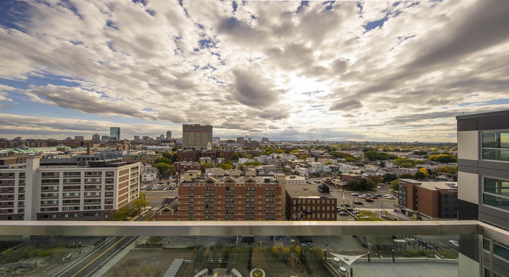 A cityscape with a mix of modern and older buildings under a cloudy sky.
