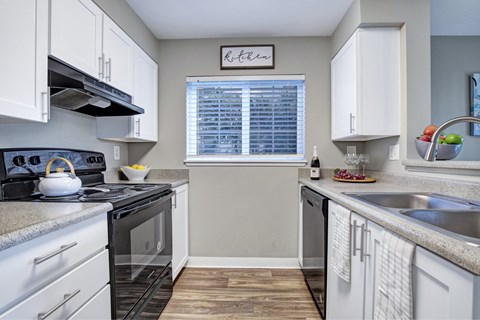 A kitchen with white cabinets and a black stove top.