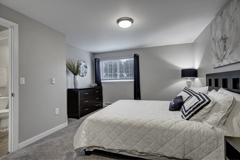A bedroom with a bed, nightstand, and window.