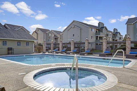 A swimming pool with a hot tub in the middle of a residential area.