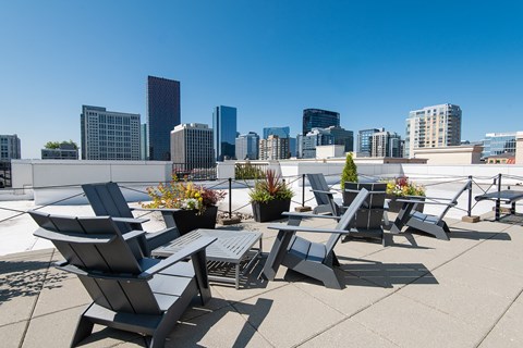A rooftop patio with chairs and a table with a city skyline in the background.