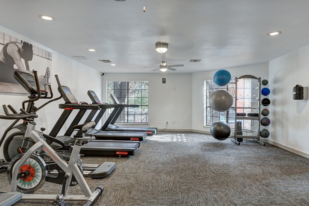 A gym with treadmills, exercise bikes, and a ball.