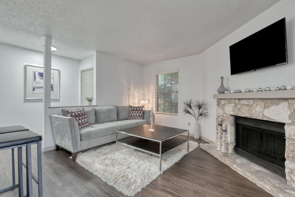 A living room with a grey couch, a coffee table, and a fireplace.