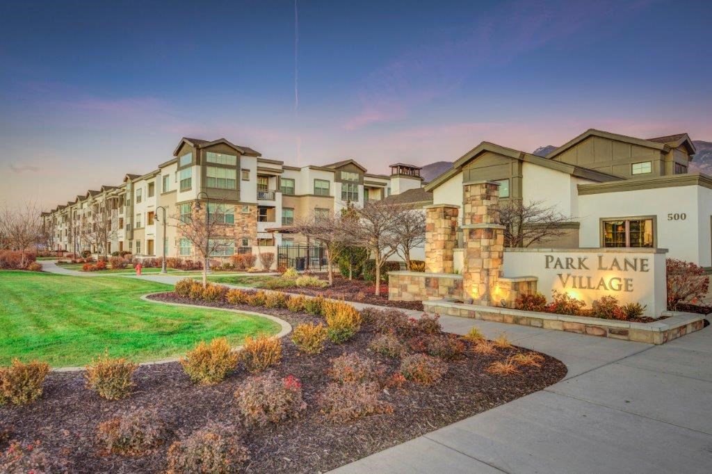 Park Lane Village apartments lit up at dusk- green and white exterior buildings