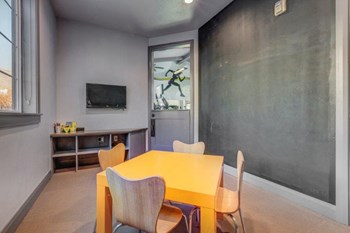 Kids room located in fitness center with small table and chairs, cubby, tv, chalk-wall, and toys - Photo Gallery 19