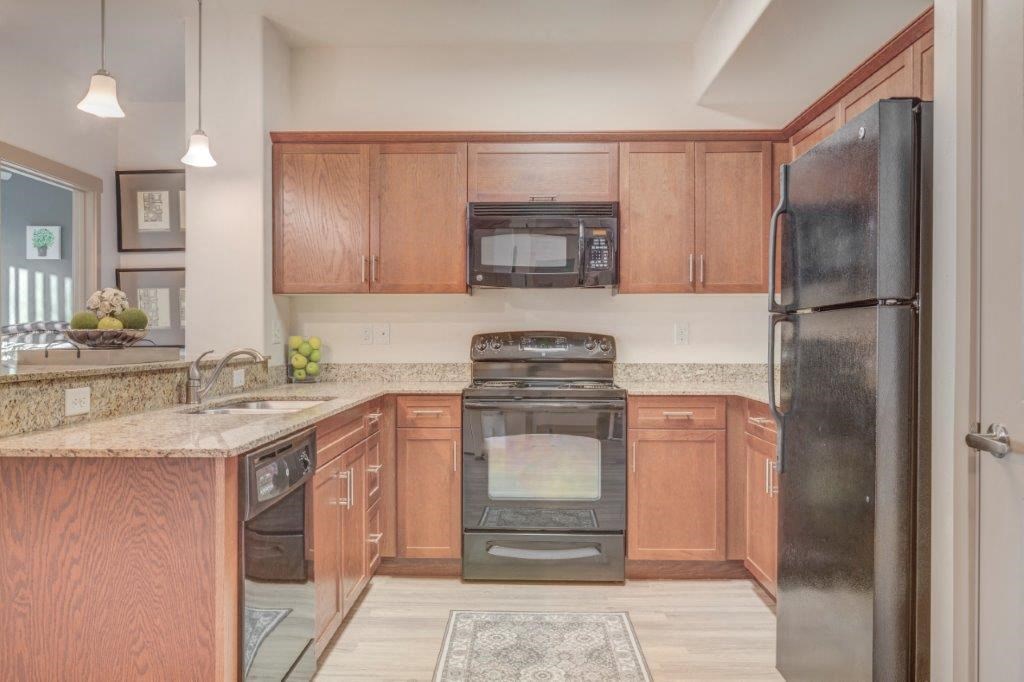 Kitchen with wood toned cabinets, black appliances