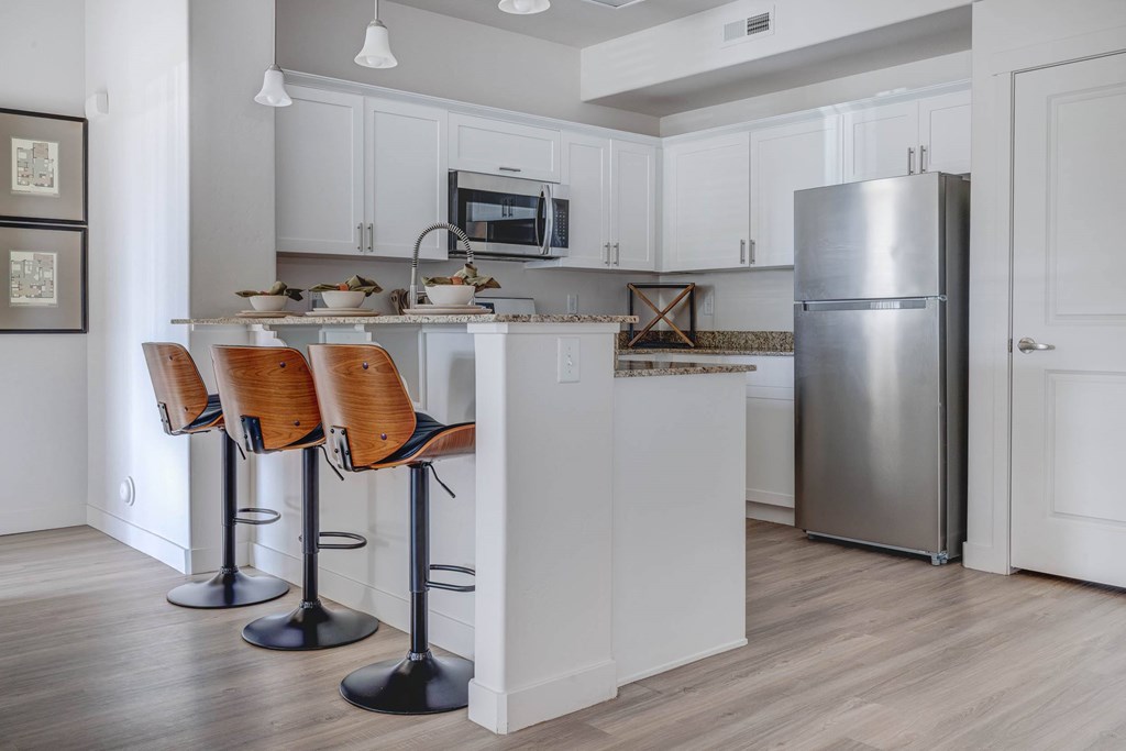 A kitchen with a white counter and bar stools.