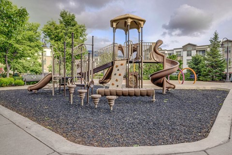 A playground with a brown and tan slide and a brown and tan swing set.