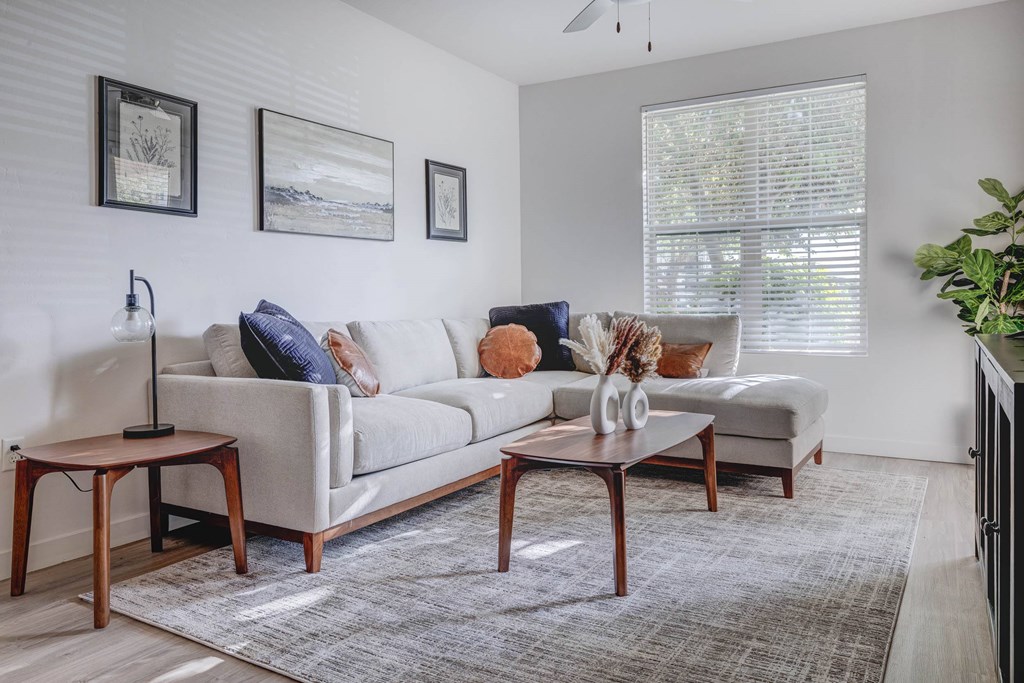 A living room with a white couch, a wooden side table, and a rug.