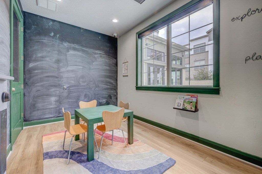 A room with a chalkboard wall and a table with chairs.