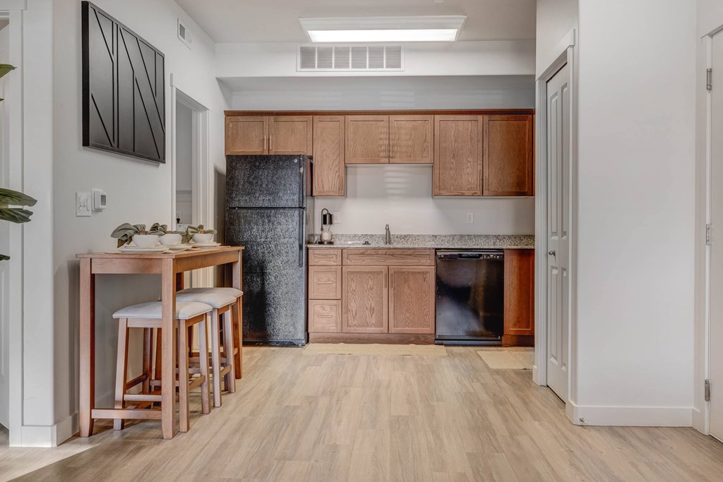 A kitchen with wooden floors and a black refrigerator.