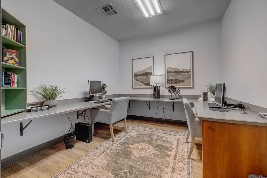 A room with a desk, chairs, and a bookshelf.