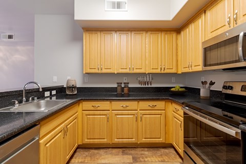 A kitchen with wooden cabinets and black countertops.