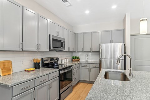 A kitchen with grey cabinets and a granite countertop.
