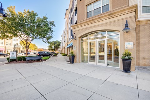 an empty sidewalk in front of a building with glass doors