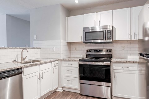 A kitchen with white cabinets and stainless steel appliances.