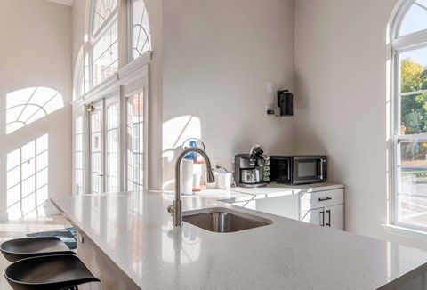 A kitchen in the clubhouse with a sink, microwave, and oven.
