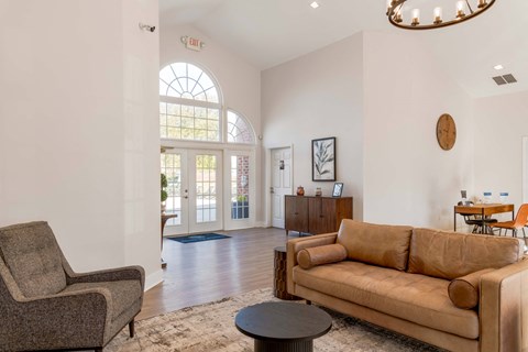 A living room with a brown couch, a grey armchair, and a coffee table.