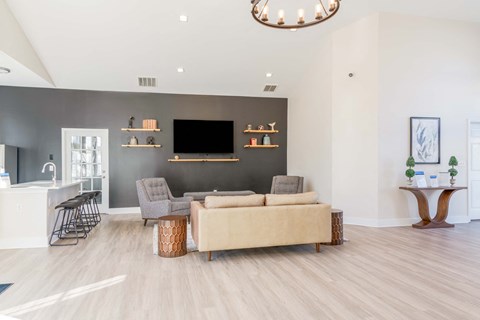 A living room in a clubhouse with a grey couch and a wooden floor.