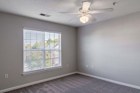 A room with a ceiling fan and a window with blinds.