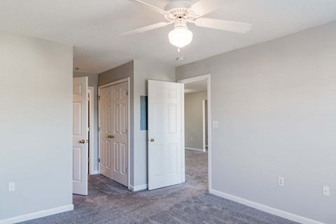 an empty bedroom with carpeted flooring and a ceiling fan