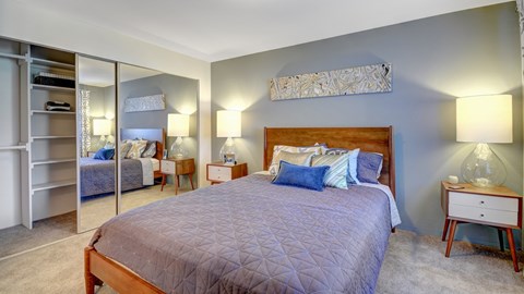 A bedroom with a large bed and a mirrored closet.