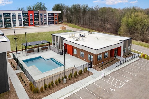 A building with a red and grey exterior has a pool in front of it.