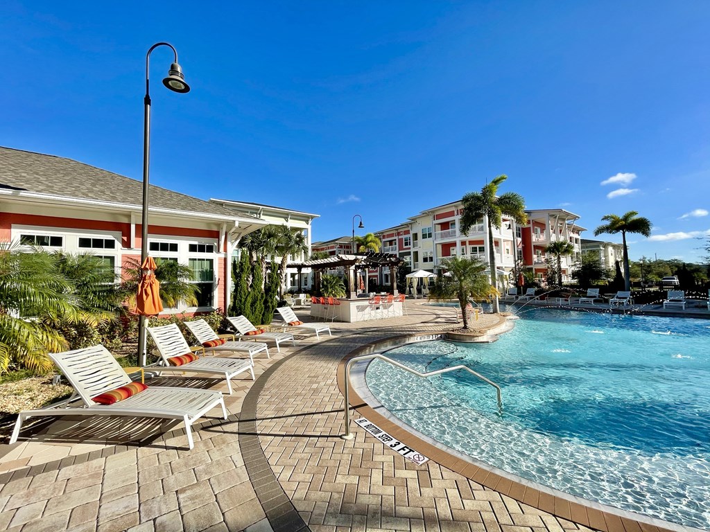 A pool with a sun lounger and a building in the background.
