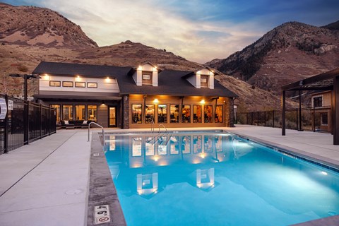 A large house with a pool in the foreground and mountains in the background.