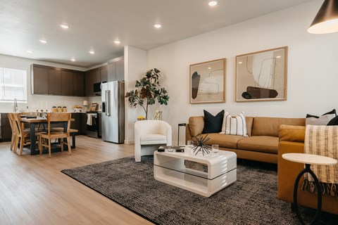 A modern living room with a white sofa, a coffee table, and a dining table with chairs.