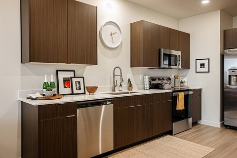 A modern kitchen with dark wood cabinets and stainless steel appliances.