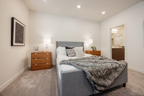 A bedroom with a large bed and a nightstand with a lamp.