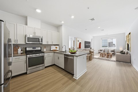 A modern kitchen with wooden floors and stainless steel appliances.