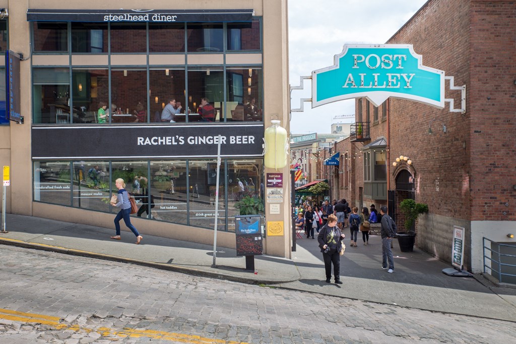 people walking down the street in front of a building with a sign that says post alley