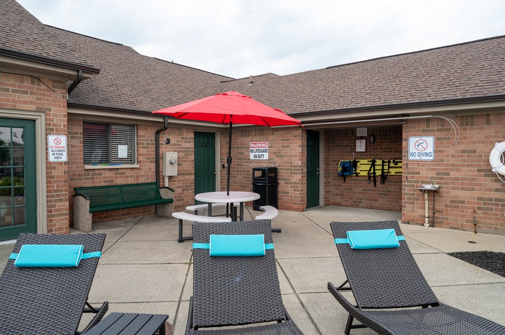 a patio with a table umbrella and lounge chairs in front of a brick building