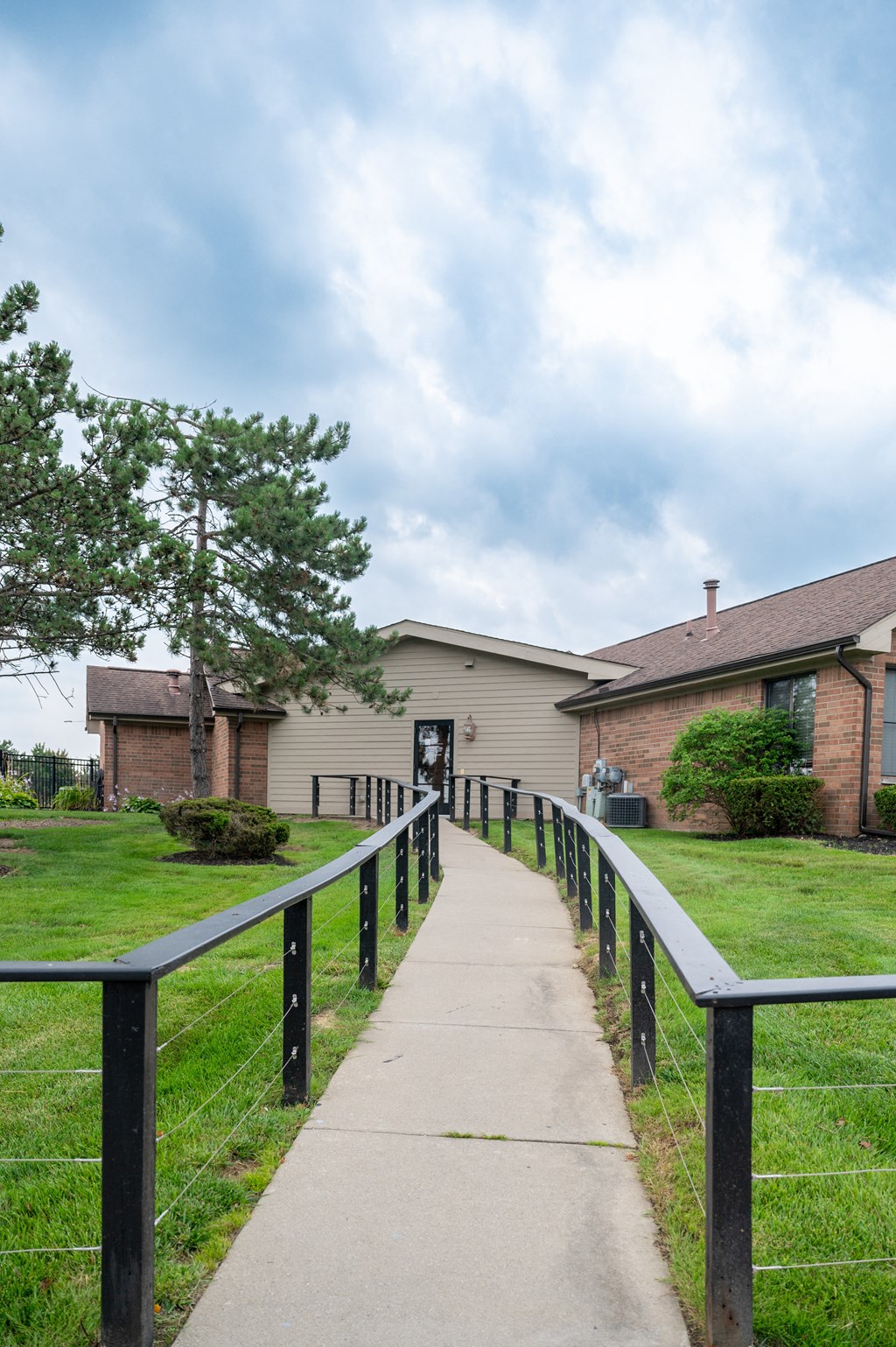 a path leading to a house with a fence on both sides of it
