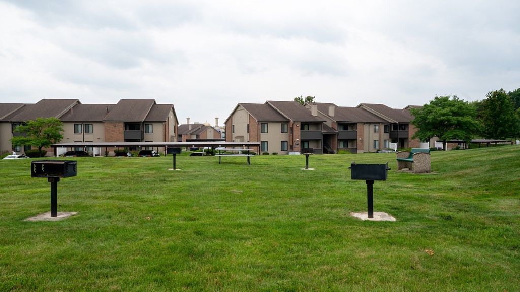 a grassy area with several rows of houses in the background