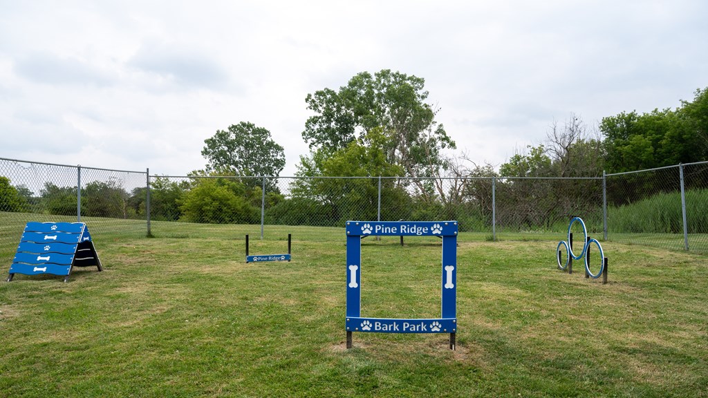a sign in the middle of a grassy field with a playground in the background