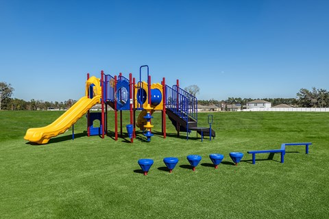 A playground with a yellow slide and blue and red play structures.