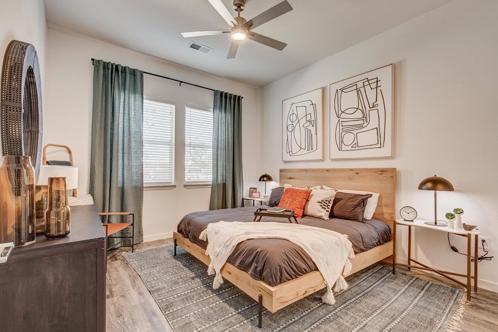 Model bedroom with window, ceiling fan and wood-style flooring