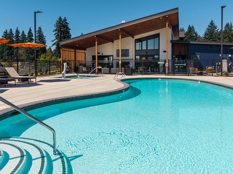 A swimming pool in front of a building with a person standing in the background.