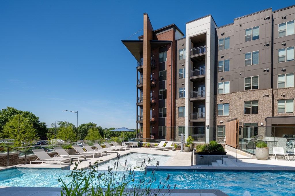 a swimming pool with lounge chairs in front of a building