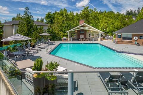 A large swimming pool surrounded by lounge chairs and umbrellas.