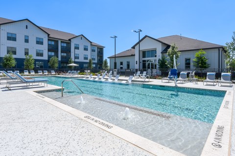 A large outdoor swimming pool with a fountain in the middle of it.