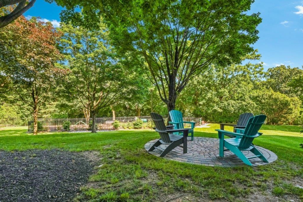 two chairs and a table in a park next to a tree