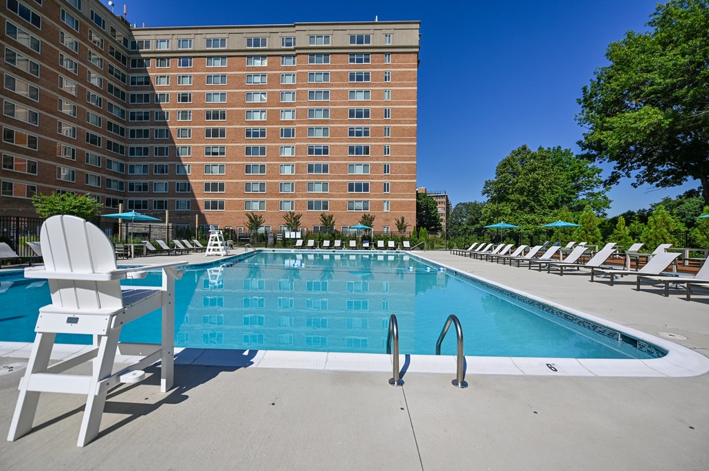 a swimming pool with chairs and a large building in the background