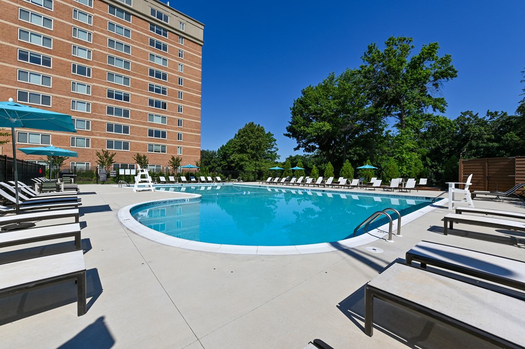 a swimming pool with chairs and a building in the background