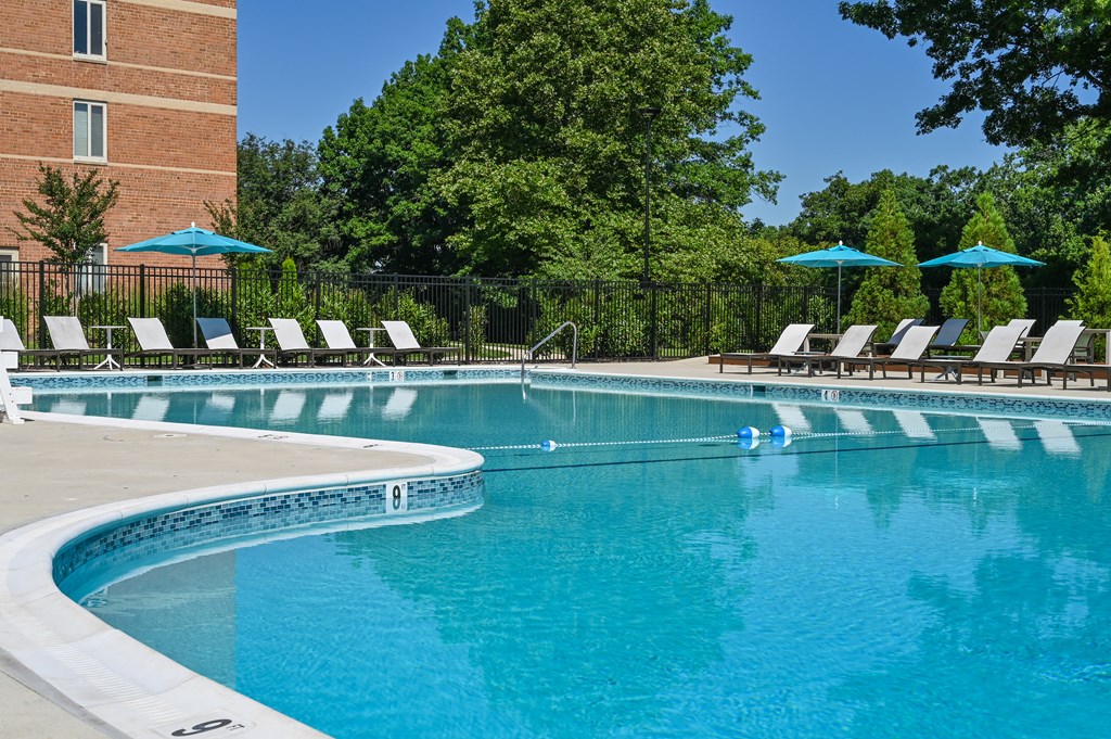 a swimming pool with chairs and umbrellas in front of a building